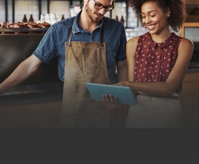 Two restaurant workers talking and looking at laptop