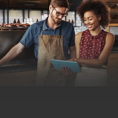 Two restaurant workers talking and looking at laptop